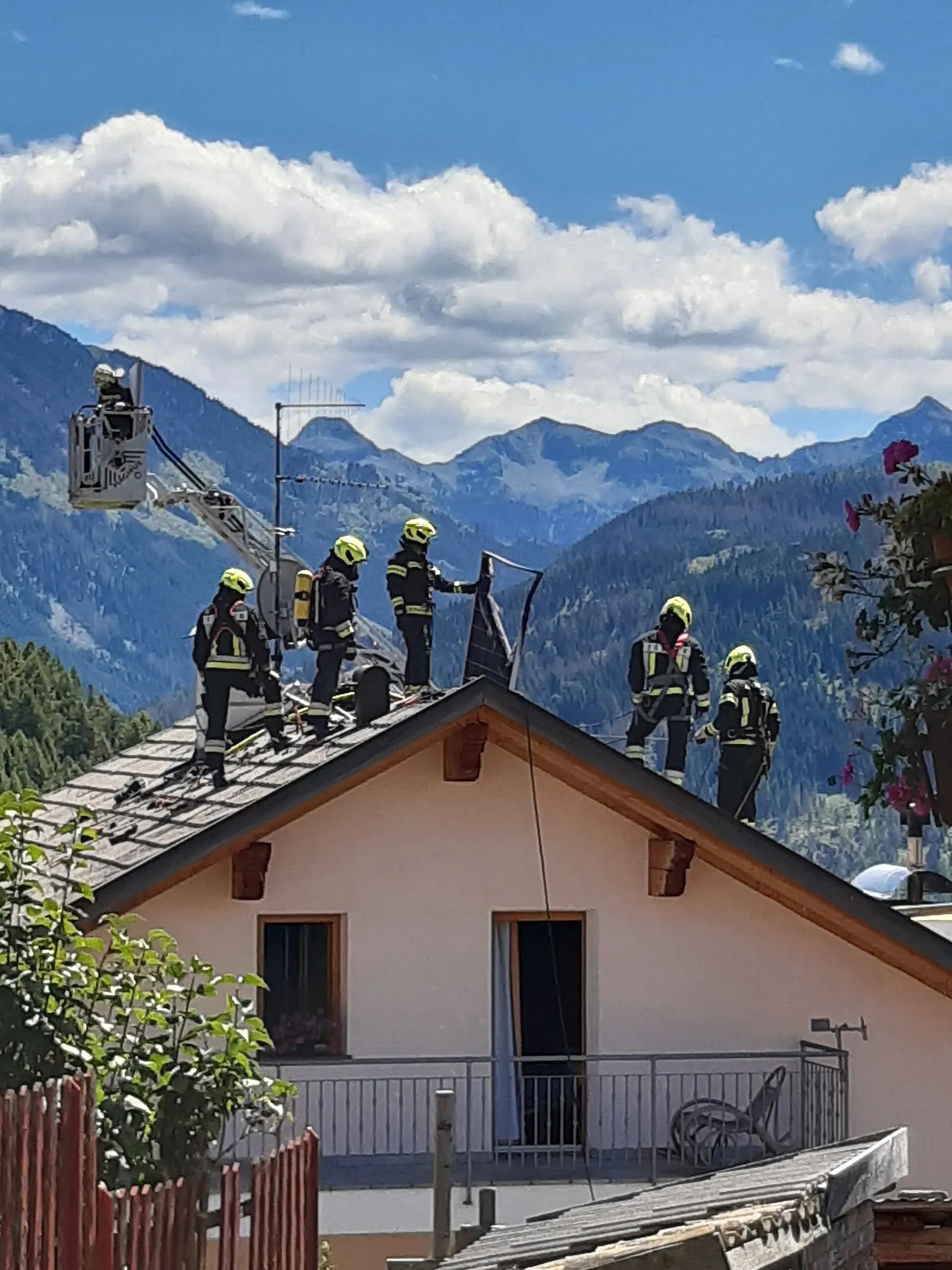 Local fire service attending a rooftop solar panel fire. The fireman atop the roofline is holding a burnt-out panel. Local SEO checklist for solar installers